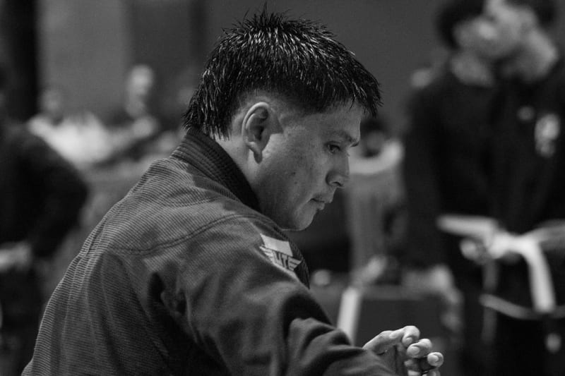 Black-and-white profile of a competitor in a black gi focused before his match.