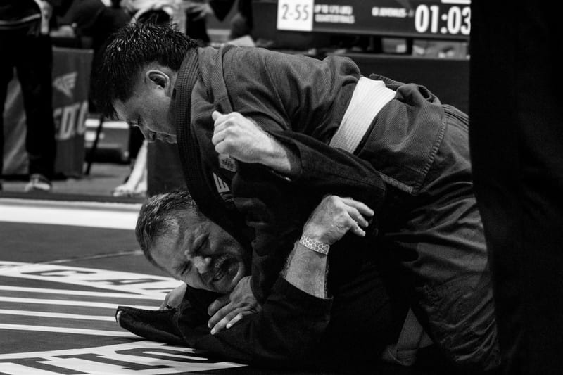 Black-and-white photo of two adults fighting for grips during a gi match.