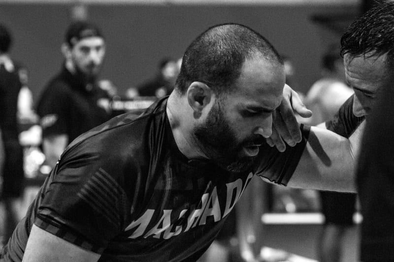 Black-and-white photo of a no-gi competitor in a Machado rashguard moving across the mat.