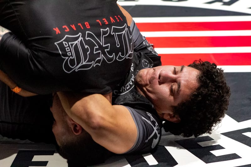 A no-gi competitor fights from the bottom during a close ground exchange.