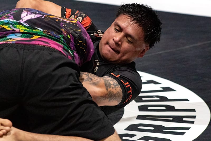 Two no-gi competitors battle on the ground during an adult match.