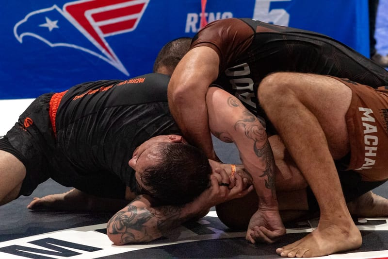 Two no-gi competitors scramble on the mat during an adult match.