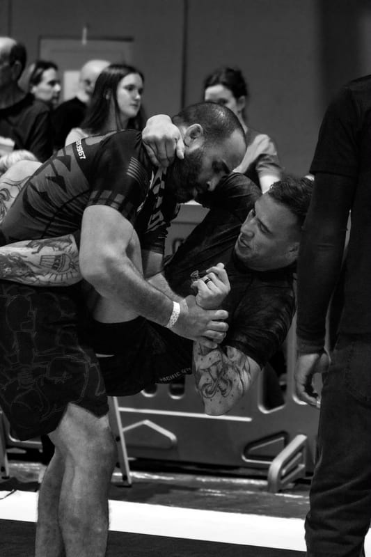 Black-and-white photo of two no-gi competitors locked in a standing clinch.