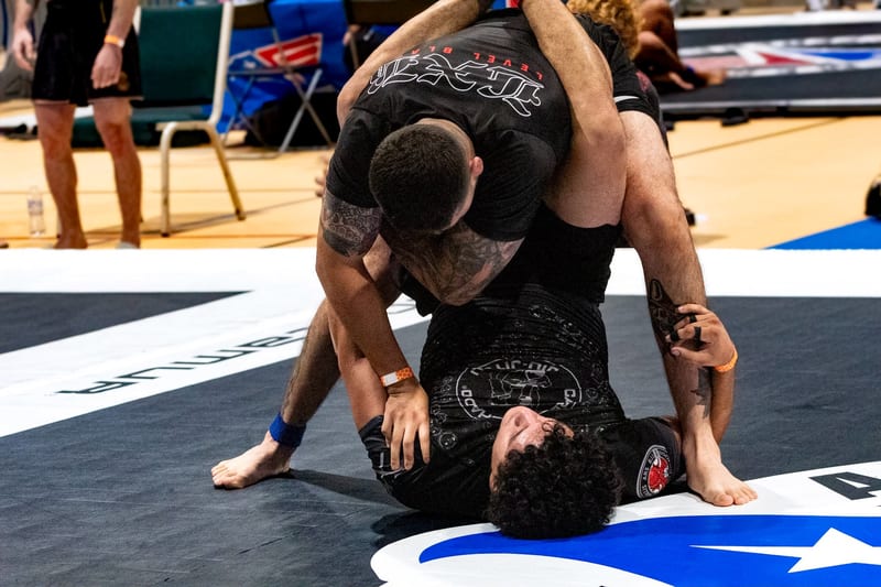 A no-gi competitor stands over his opponent working to pass during an adult match.