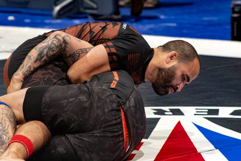 A no-gi competitor controls his opponent from top position during an adult match.