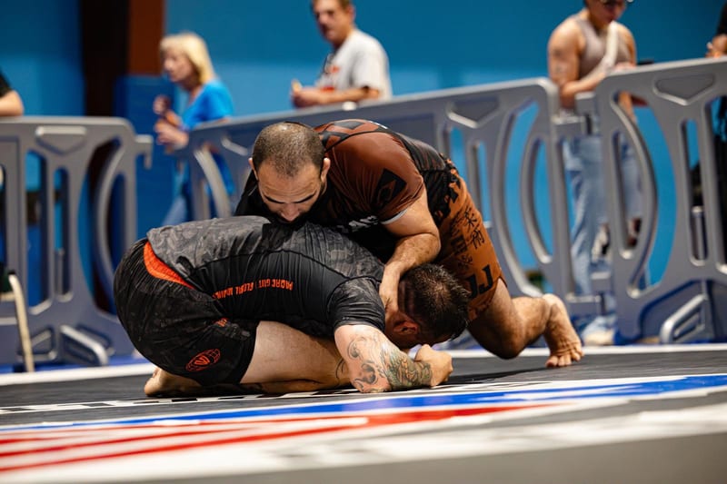 A no-gi competitor rides on top of his opponent during an adult match.