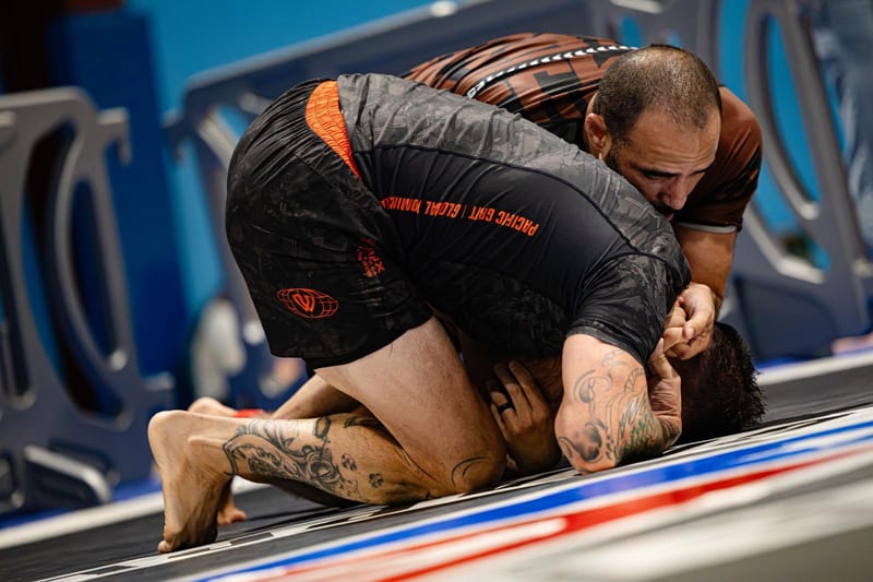 A no-gi competitor attacks his turtled opponent during an adult match.