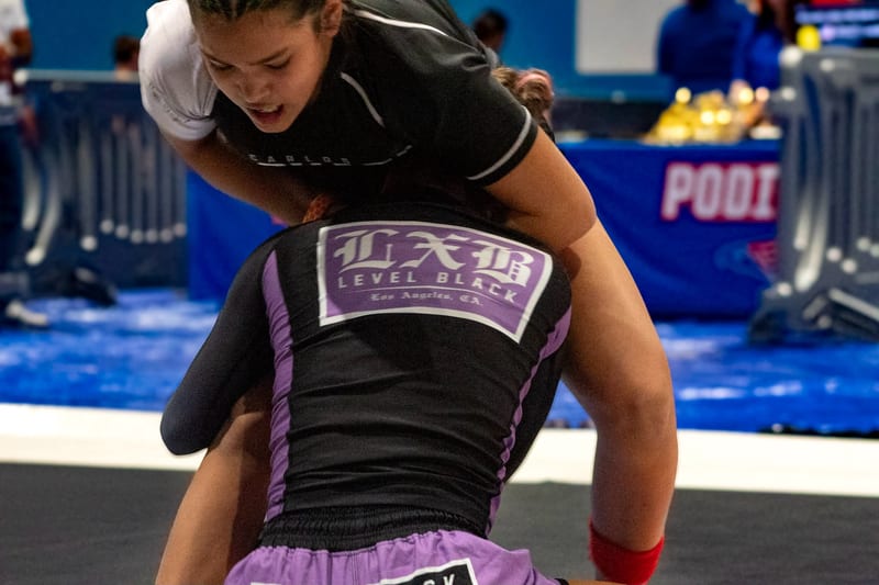 A young competitor controls his opponent from behind during a kids no-gi match.