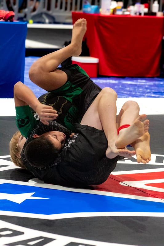 Two boys scramble for position in a kids no-gi match.