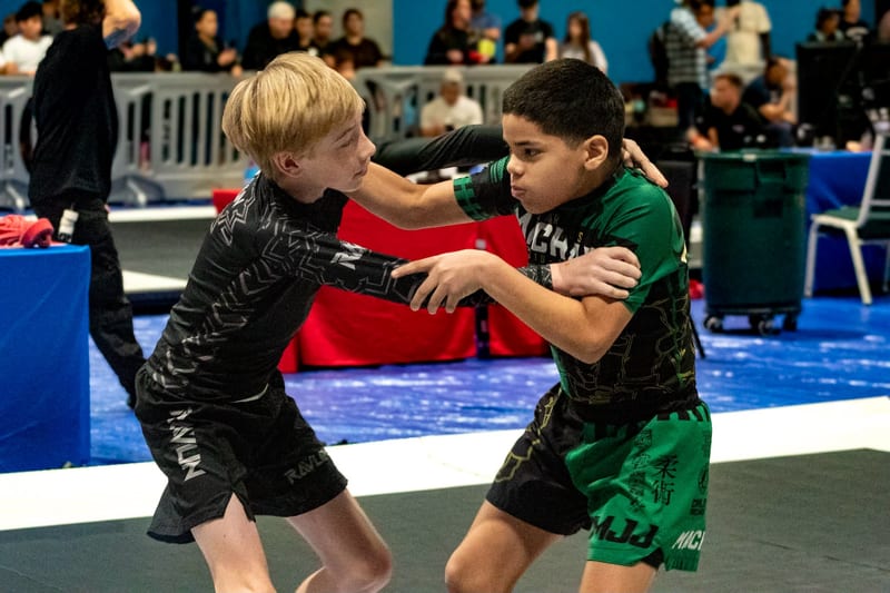 Two boys clash in a standing tie-up during a kids no-gi match.