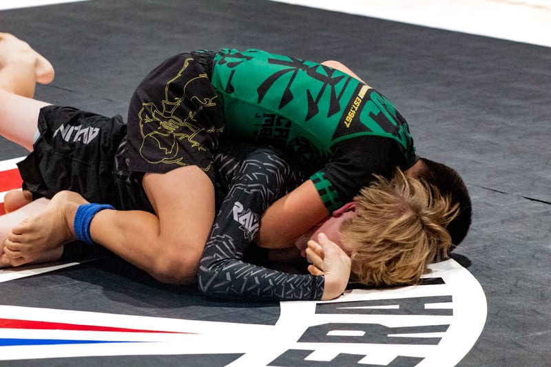 Two boys scramble on the ground during a kids no-gi match.
