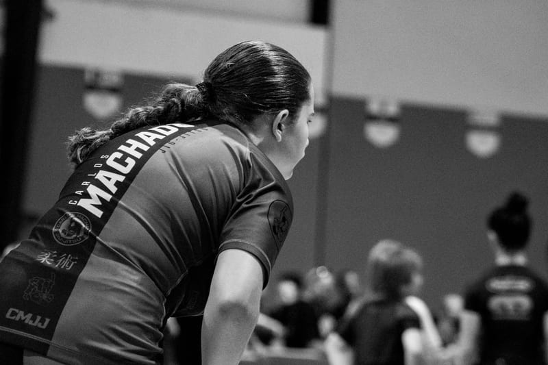 Black-and-white photo of a girl in a Machado rashguard setting up before her match.