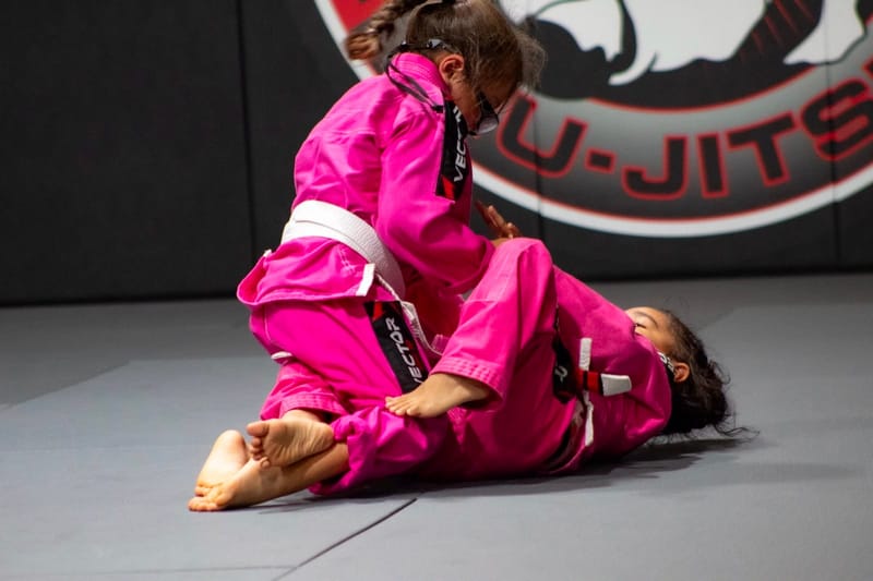 Two girls in pink gis rolling together