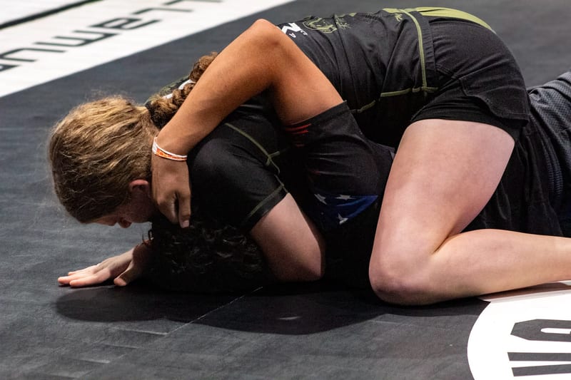 Two girls scramble on the ground during a no-gi match.