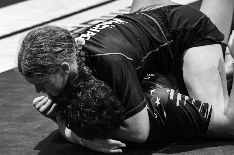 Black-and-white photo of two girls grappling on the ground in a no-gi match.