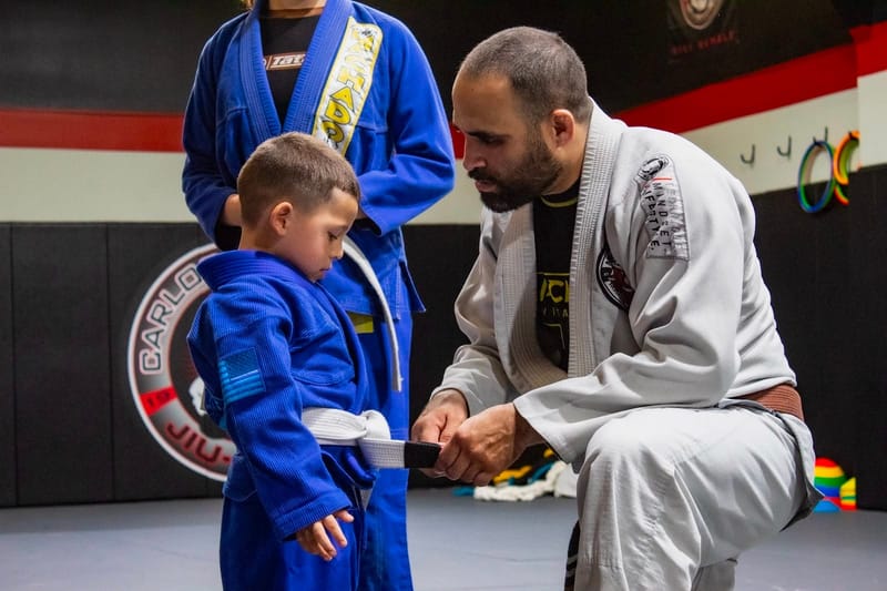A boy in a blue gi at a belt ceremony