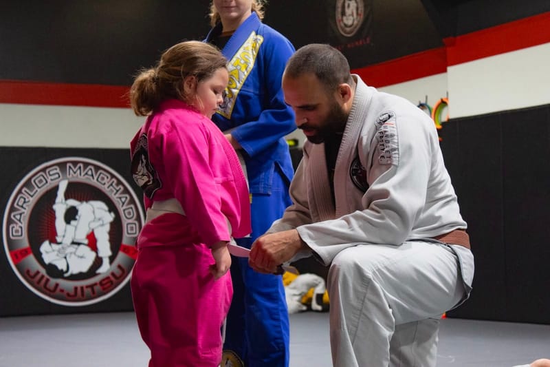 A girl in a pink gi at a belt ceremony
