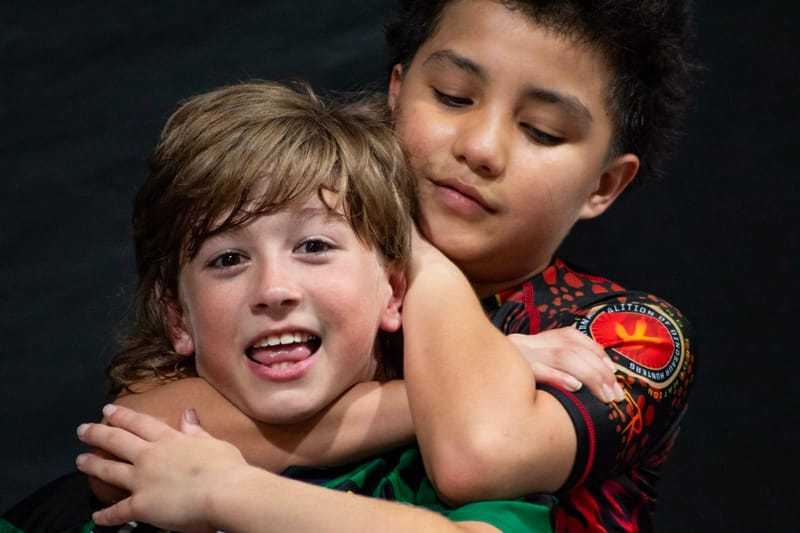 Two young teammates hugging and smiling after class