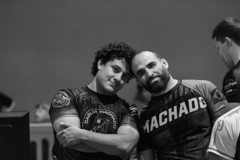 Black-and-white photo of two teammates in Machado rashguards posing together at the tournament.