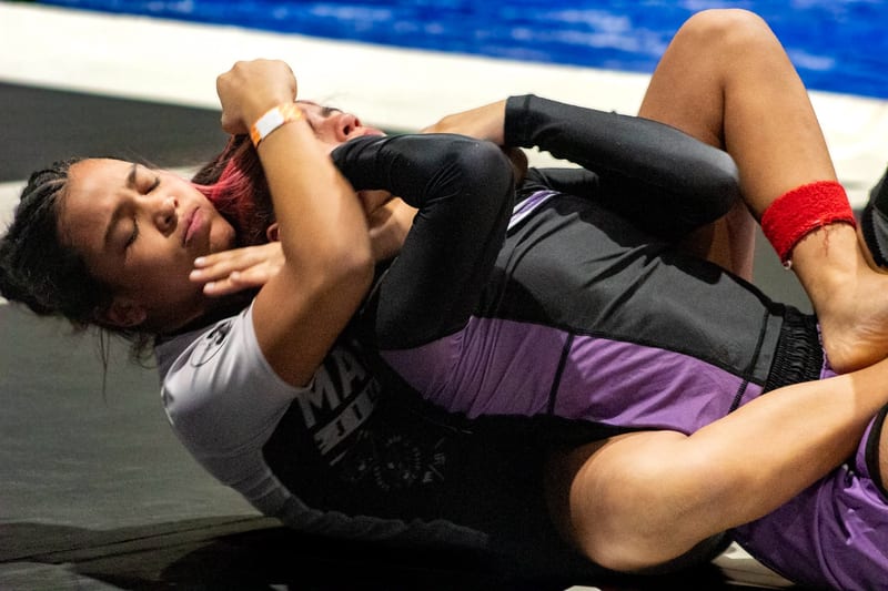 A woman works from the bottom during a women's no-gi match.